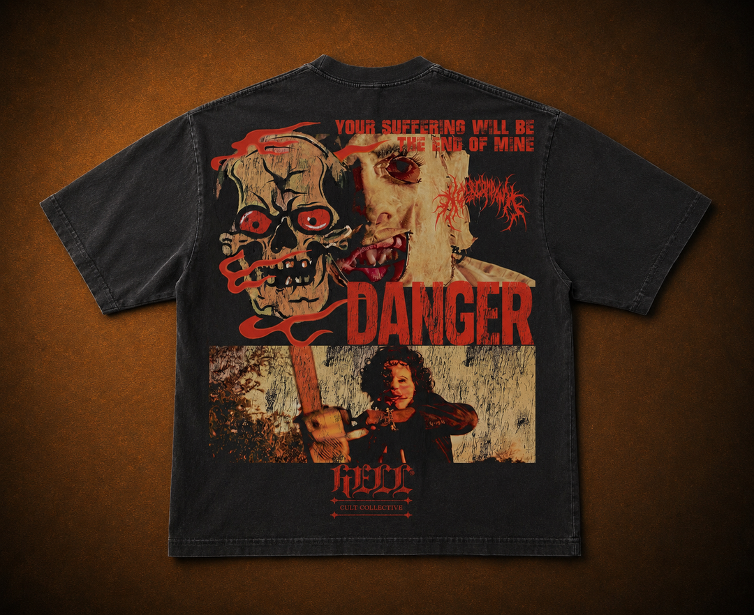 A black graphic t-shirt featuring a horror-themed print with a skull, a screaming face, a figure holding a bloody knife, and the words 'DANGER' and 'HELL'. The shirt is displayed flat against a dark brown textured background. texas chainsaw massacre