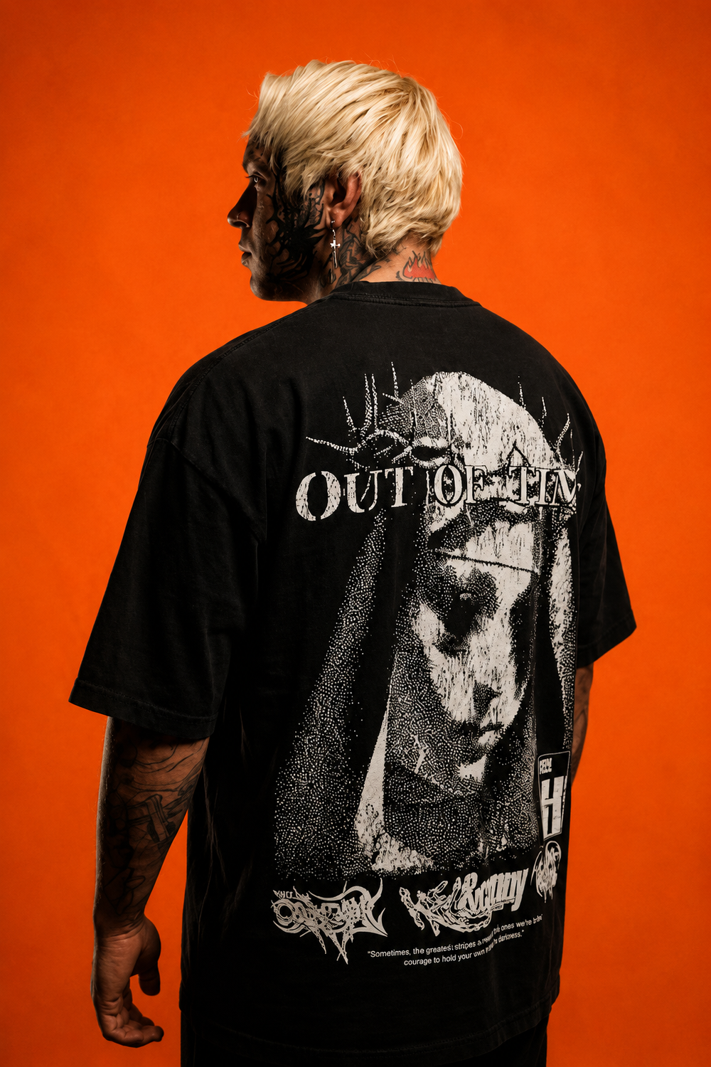 Person wearing a black t-shirt with graphic design and text on the back against an orange background