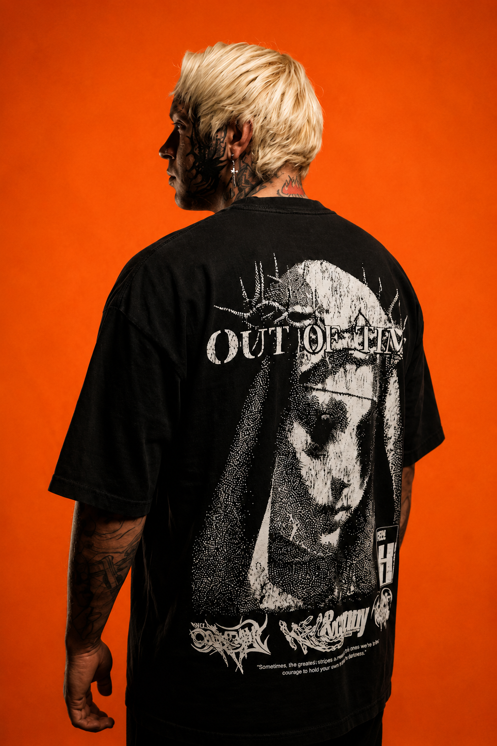 Person wearing a black t-shirt with graphic design and text on the back against an orange background