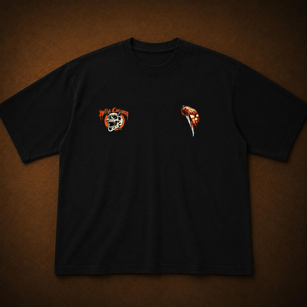 A black short-sleeve t-shirt laid flat on a textured brown background, featuring a small orange and white graphic on the left chest and a small orange graphic on the right chest.