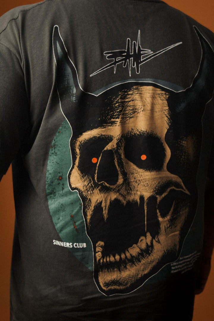 Black t-shirt with a graphic design of a skull and text on the back against a brown background