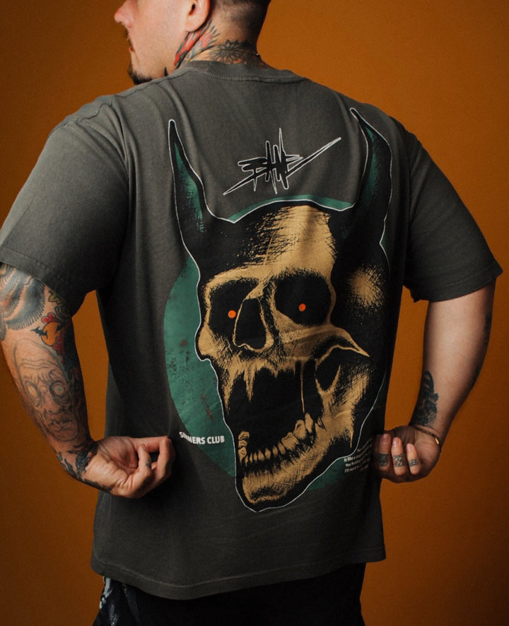Person wearing a black t-shirt with a skull design on the back against an orange background