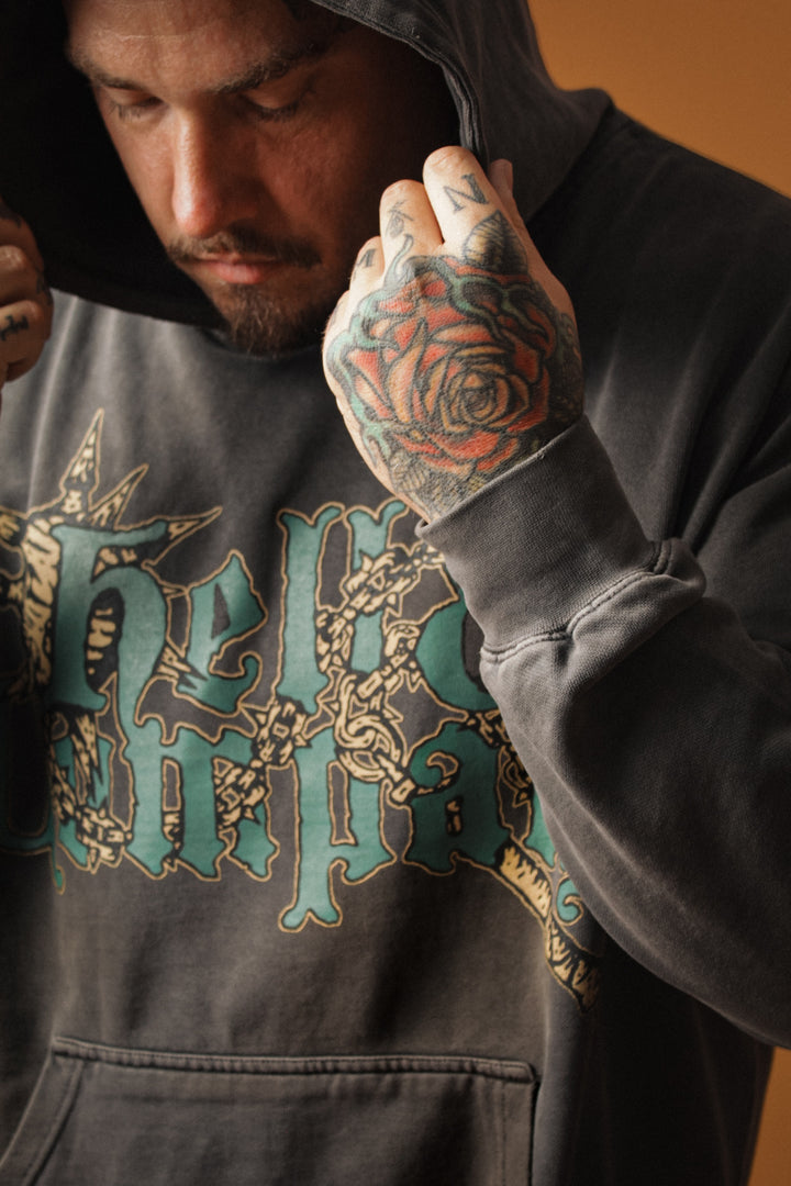 Man wearing a hoodie with a graphic design, focusing on the text and tattoos.