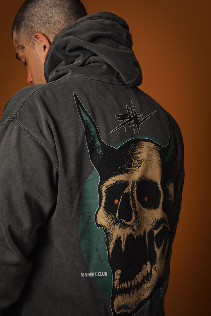 Person wearing a dark jacket with a skull design on the back against an orange background