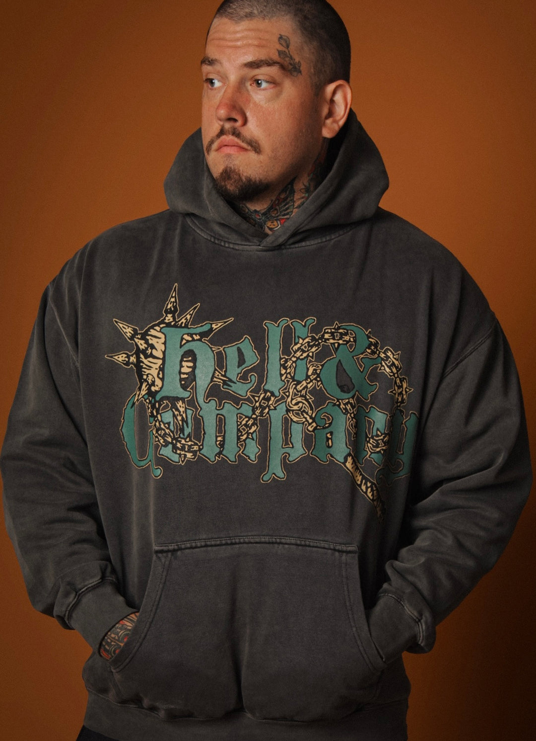 Man wearing a black hoodie with a logo on a brown background