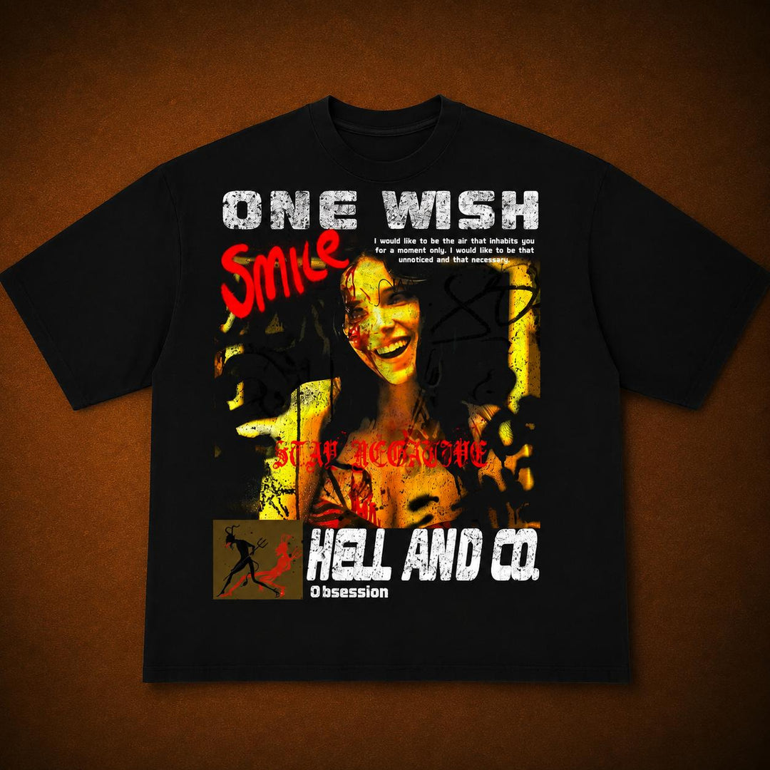 A black short-sleeve graphic T-shirt laid flat against a textured brown background. The shirt features a large distressed print with the text 'ONE WISH' in white, 'Smile' in red, 'Hell and Co.